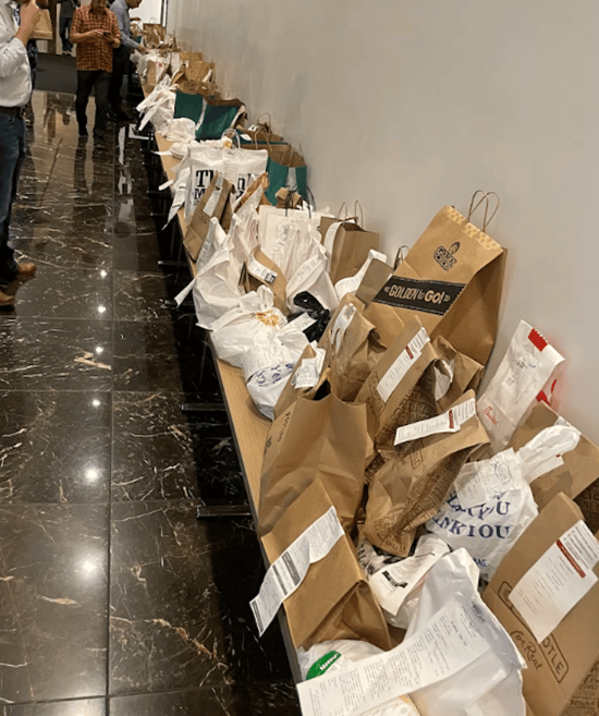 A messy multifamily residential hallway filled with food deliveries chaotically arranged on a table.