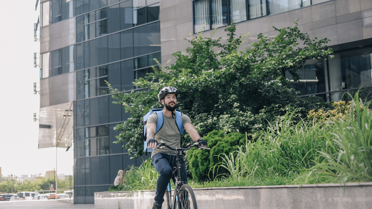 A man riding his bike outside a multifamily residential building.