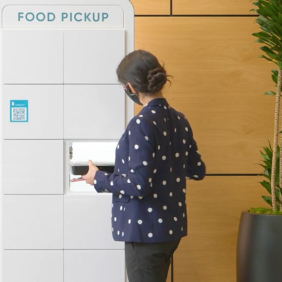 Woman reaching into food delivery locker.